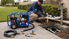 Technician connecting a portable hydrostatic line tester to an outdoor commercial water system.