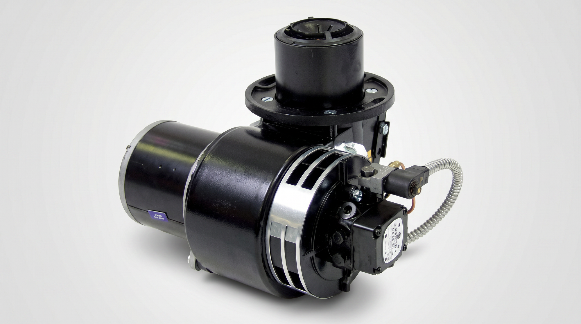 Industrial oil burner assembly with electric motor, blower housing, fuel valve, and flexible conduit.