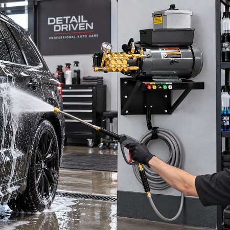 the 4000 PSI Wall Mount Electric Pressure Washer in use, with a person spraying a wet black car in a garage setting. 
